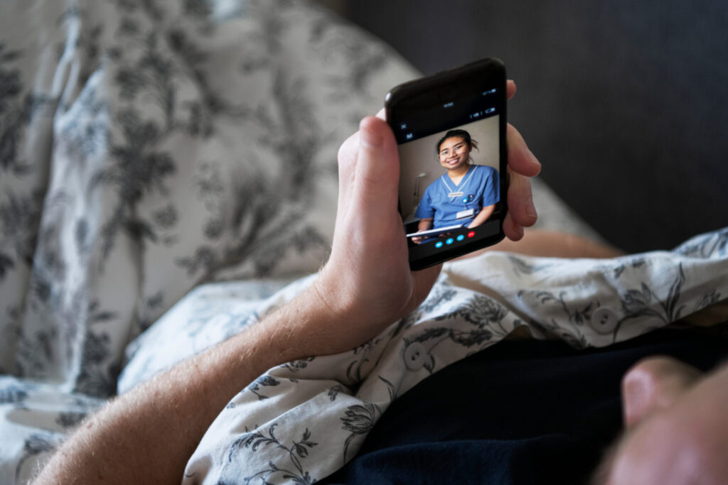 Sängliggande erson har digitalt möte med vårdpersonal